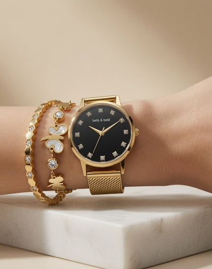 Gold watch with black face on a wrist, wearing additional gold bracelets.