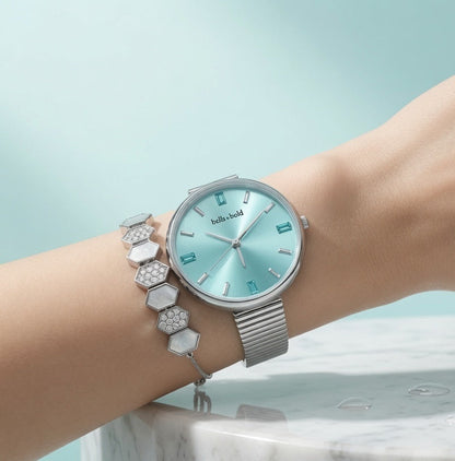 Silver watch with a turquoise face on a wrist against a light blue background